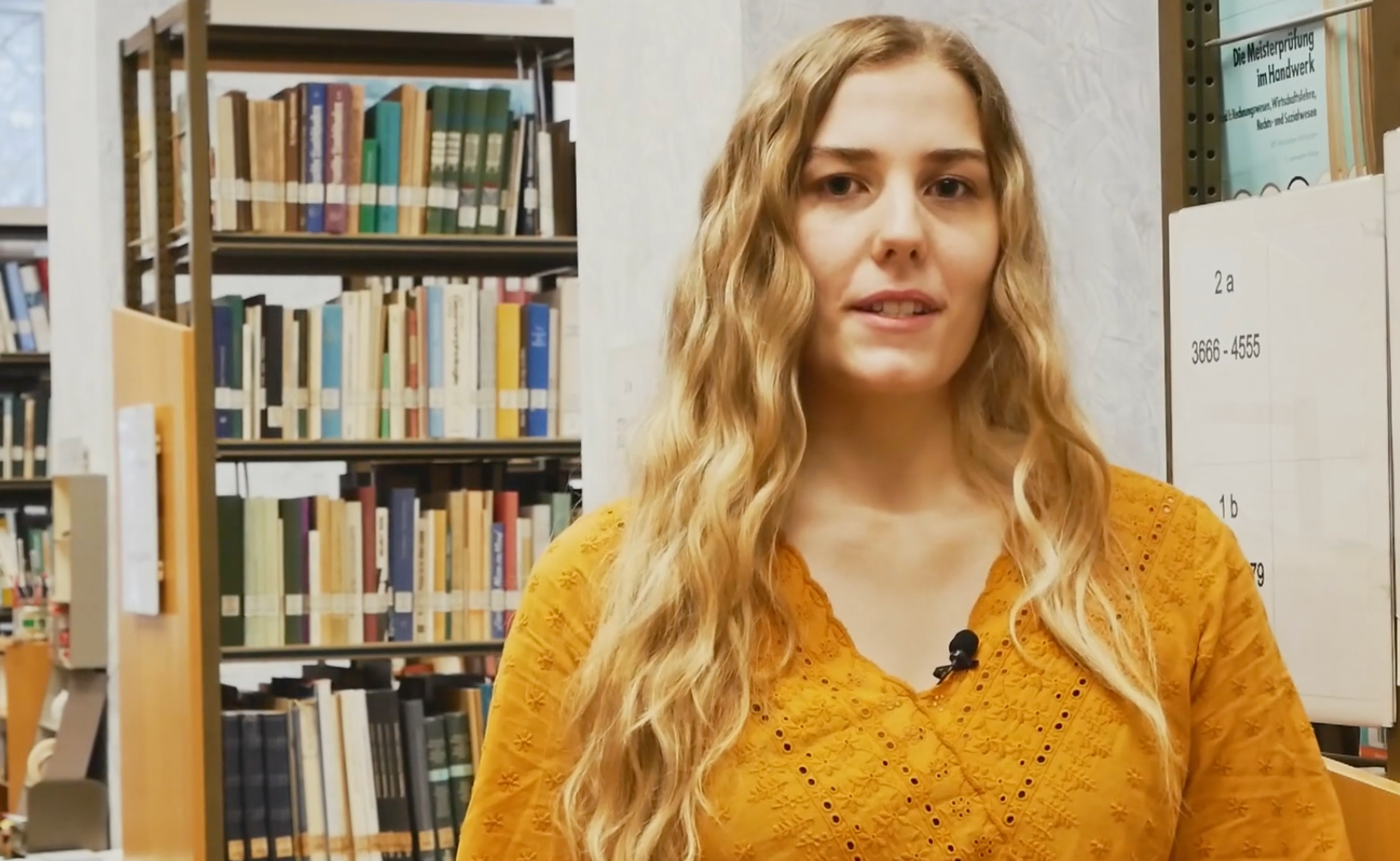 Auszubildende Maren vor Bücherregalen in der Pfalzbibliothek
